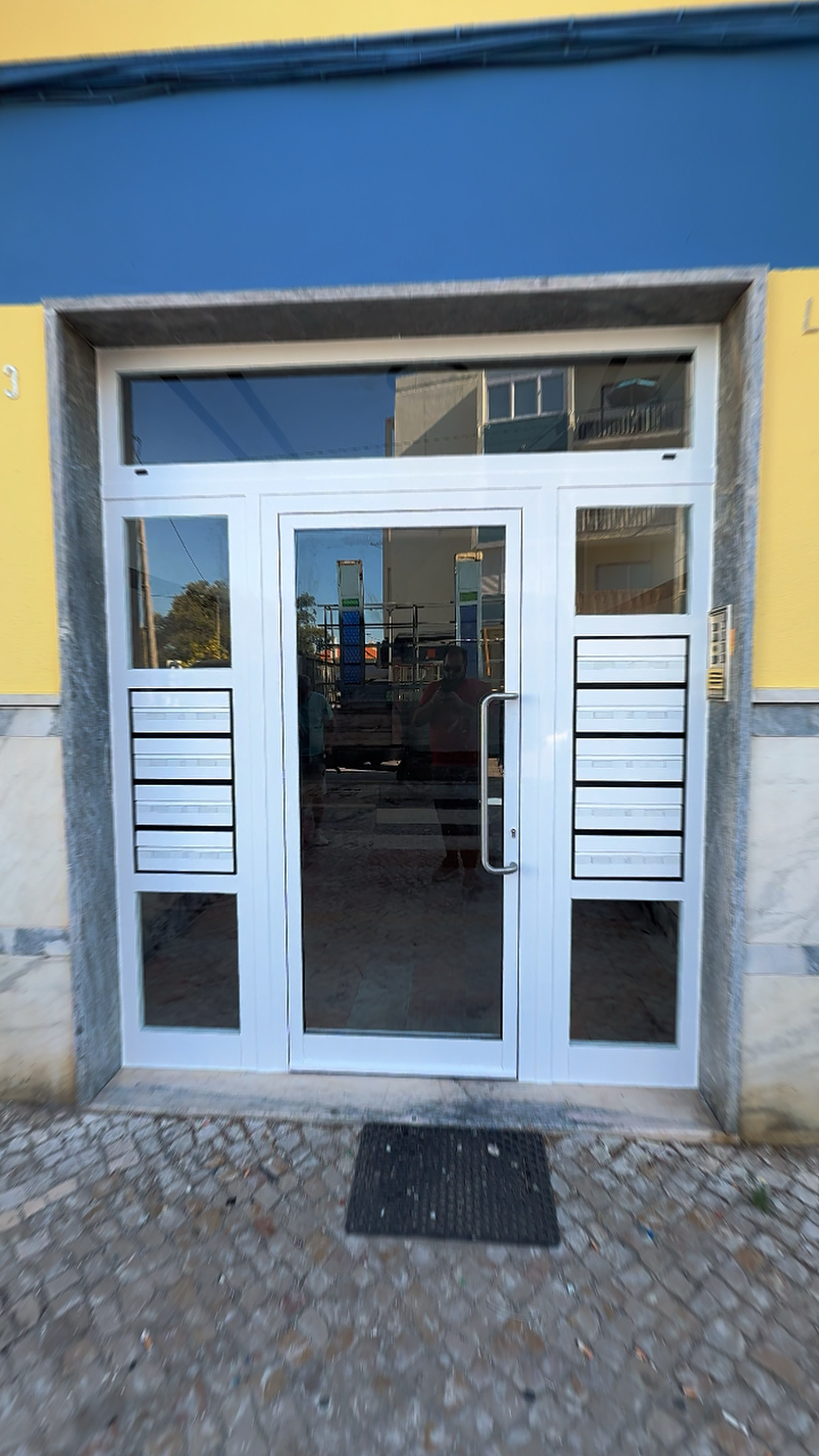 Porta branca envidraçada com fixos laterais e caixas de correio